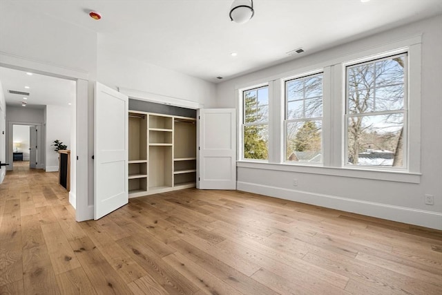 unfurnished bedroom with light wood-style flooring, a closet, visible vents, and baseboards