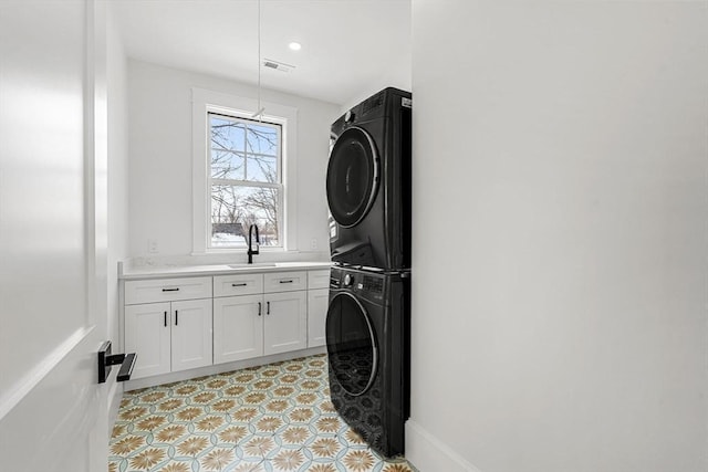 laundry room with a sink, visible vents, stacked washer / drying machine, cabinet space, and light floors