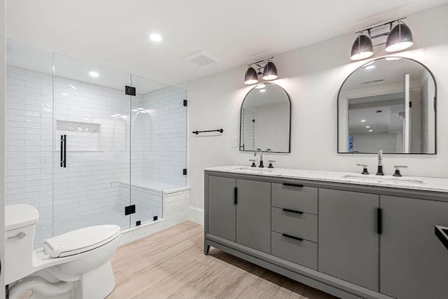 bathroom with a stall shower, wood finish floors, a sink, and toilet