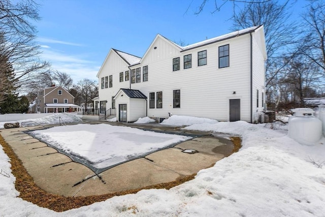 snow covered rear of property with board and batten siding