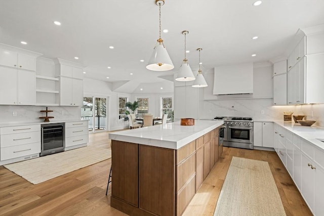 kitchen with range with two ovens, open shelves, light wood-style flooring, a kitchen island, and beverage cooler