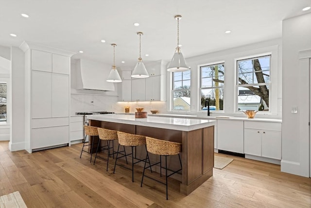 kitchen with a center island, custom exhaust hood, light countertops, high end stainless steel range oven, and light wood-style flooring