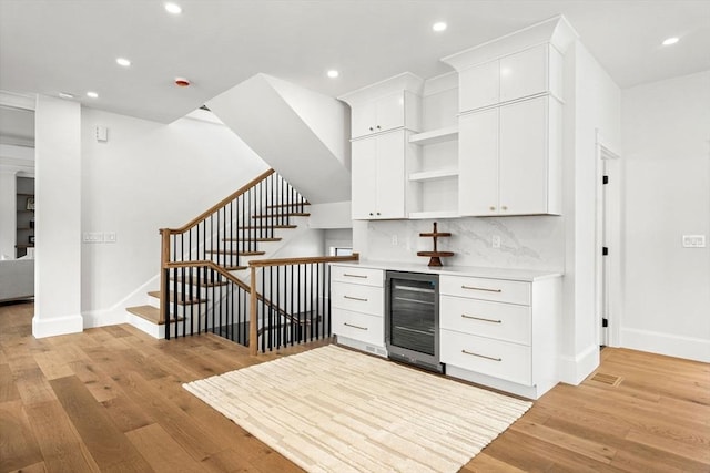 kitchen with beverage cooler, backsplash, light wood finished floors, and open shelves
