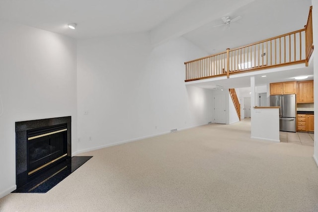 84 Pine Grove Dr Unit 84, South Hadley, MA 01075 - unfurnished living room with light colored carpet, ceiling fan, a fireplace with flush hearth, stairway, and high vaulted ceiling