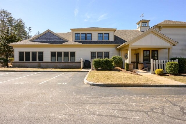 exterior space featuring a shingled roof and uncovered parking