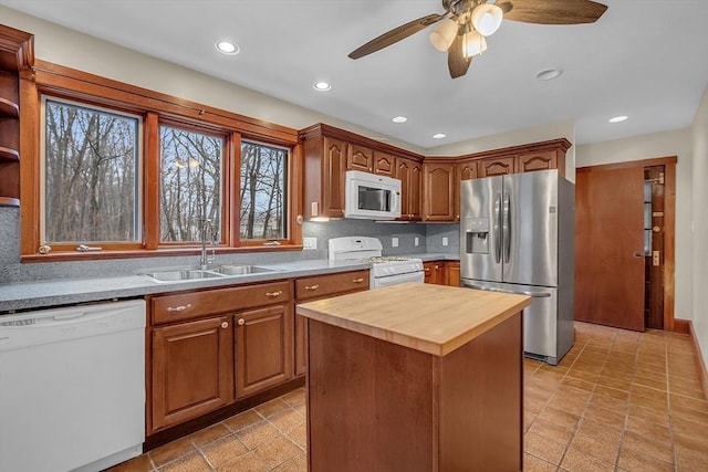 kitchen with wood counters, a center island, white appliances, sink, and ceiling fan