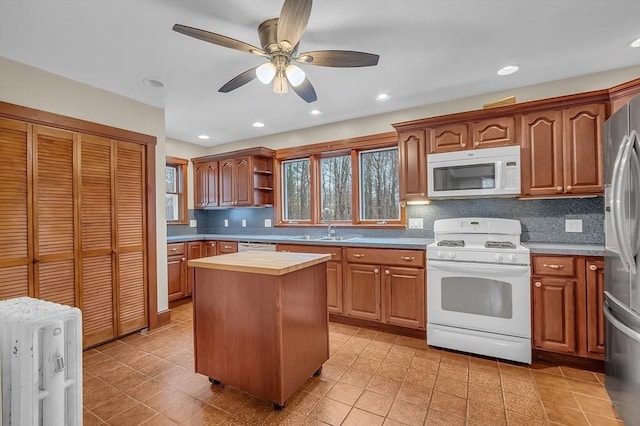 kitchen with a center island, white appliances, sink, ceiling fan, and tasteful backsplash