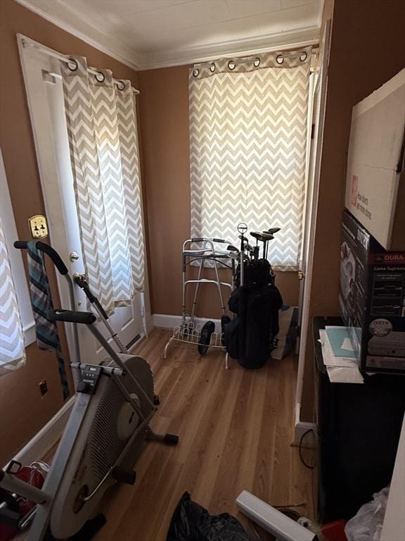 exercise area featuring crown molding, baseboards, and wood finished floors