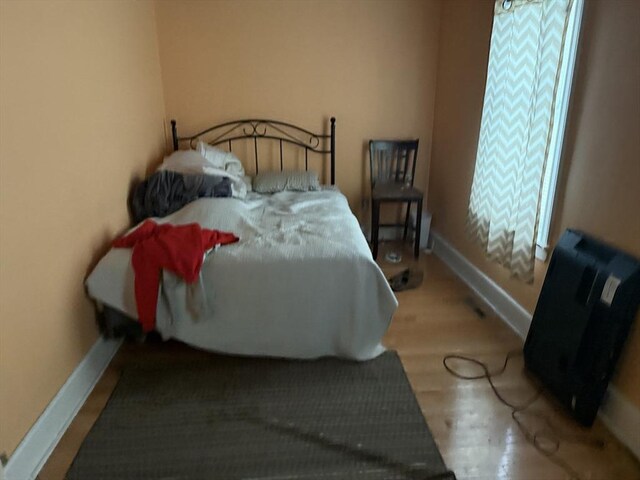 bedroom featuring baseboards, multiple windows, and wood finished floors