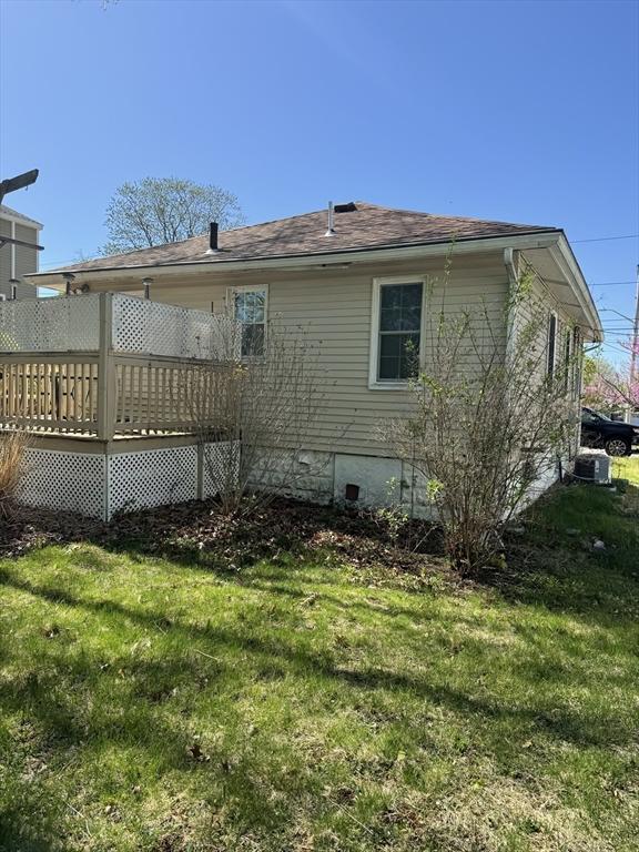 view of side of property with a lawn, a wooden deck, and crawl space