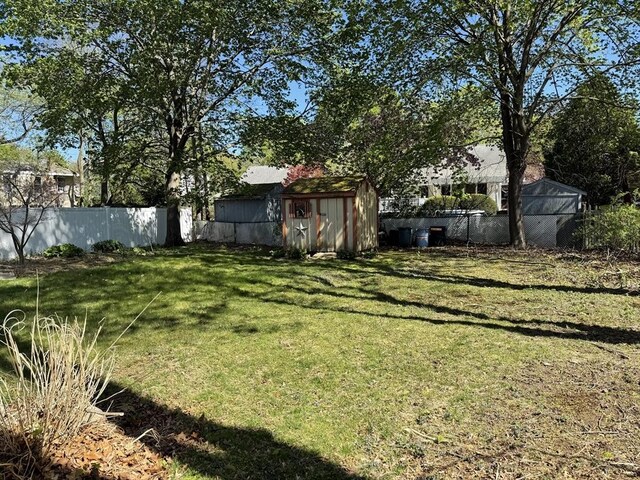 view of yard with an outbuilding, fence, and a storage shed