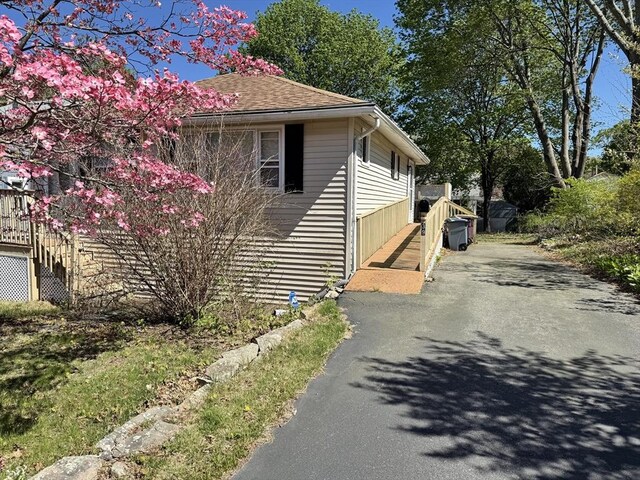 view of side of property with roof with shingles and aphalt driveway