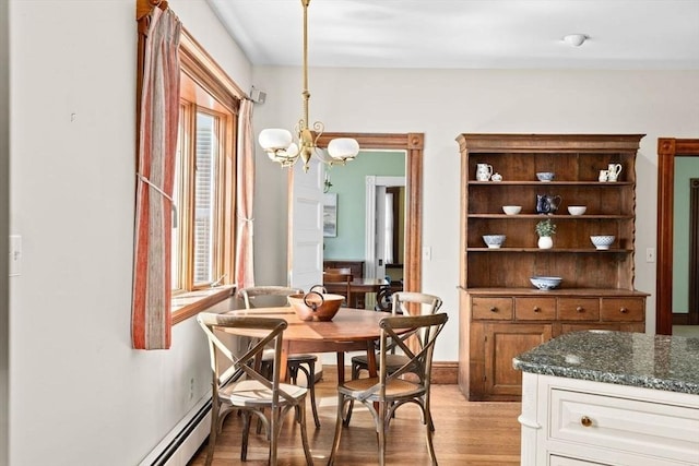 dining area with a baseboard radiator, light wood finished floors, and a notable chandelier