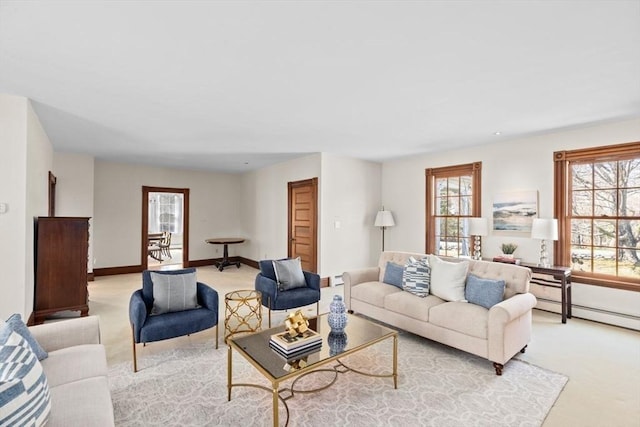 living area featuring light carpet, a healthy amount of sunlight, baseboards, and a baseboard radiator