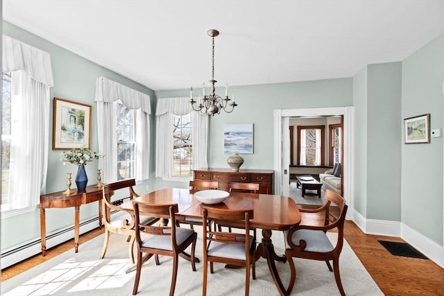 dining space featuring visible vents, a baseboard radiator, light wood finished floors, baseboards, and a notable chandelier