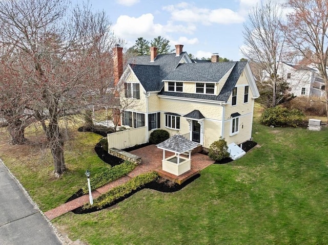 back of property featuring a chimney and a lawn