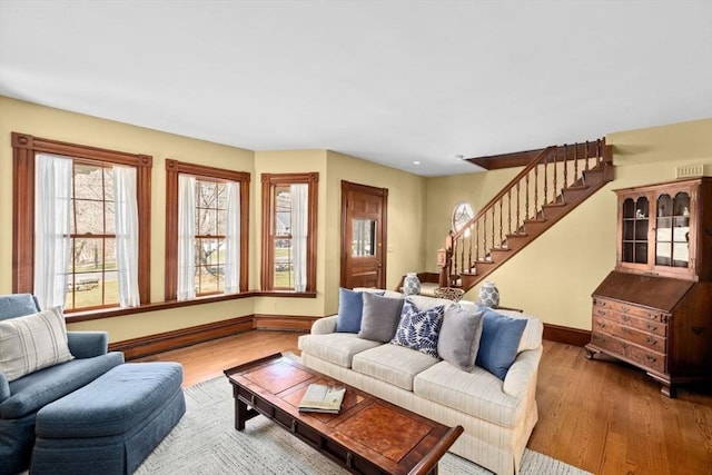 living room with wood finished floors, baseboards, and stairs
