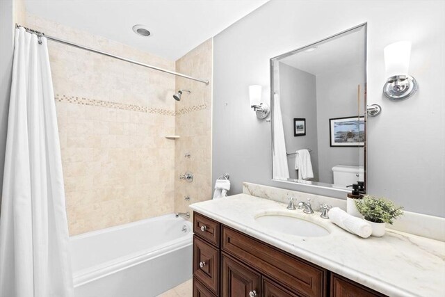 bathroom featuring toilet, shower / bath combo with shower curtain, and vanity