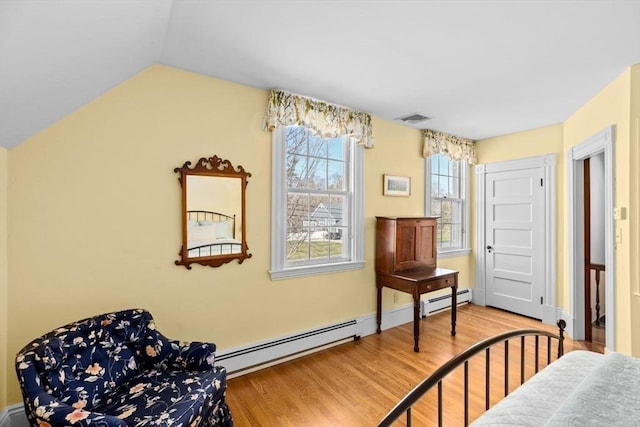 interior space with visible vents, vaulted ceiling, wood finished floors, and baseboard heating