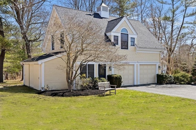view of front of home featuring roof with shingles, a chimney, a front lawn, aphalt driveway, and a garage