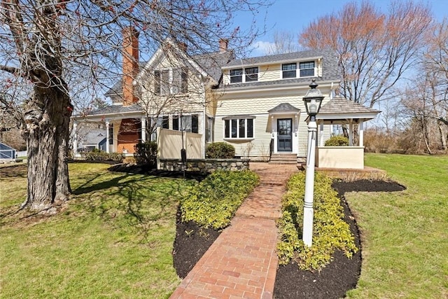 view of front of home with a chimney and a front lawn