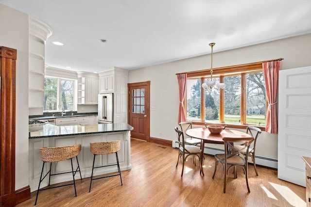 kitchen with baseboards, high end fridge, a peninsula, open shelves, and light wood-style floors