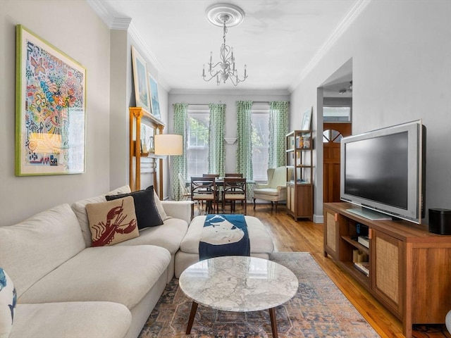 living room with crown molding, a chandelier, and light wood finished floors