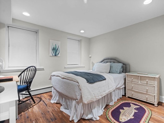 bedroom featuring a baseboard heating unit, wood finished floors, recessed lighting, and baseboards