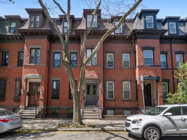 townhome / multi-family property featuring brick siding and mansard roof