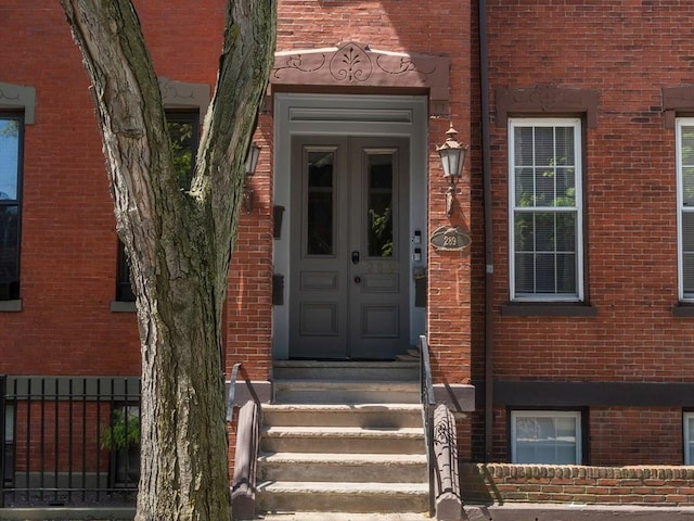view of exterior entry featuring french doors and brick siding