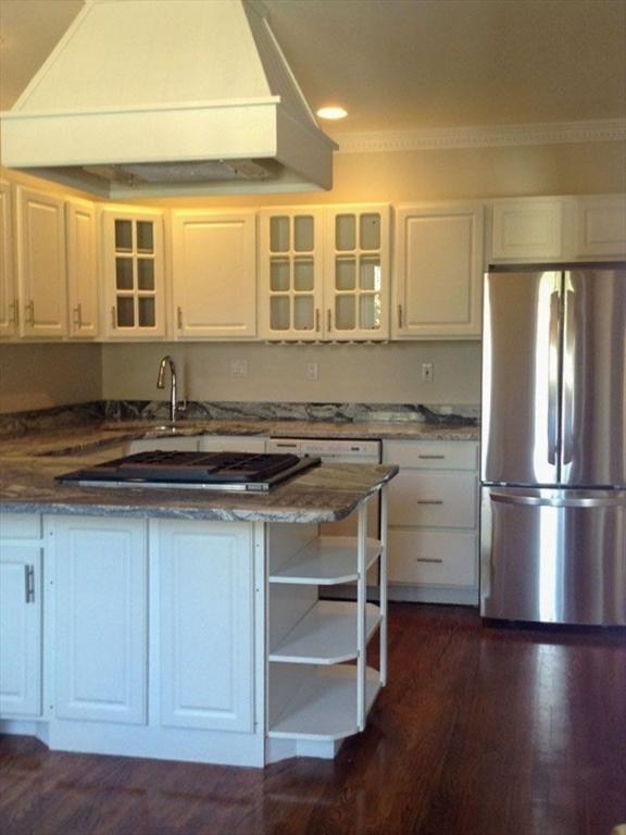 kitchen featuring freestanding refrigerator, custom exhaust hood, white cabinets, gas cooktop, and glass insert cabinets