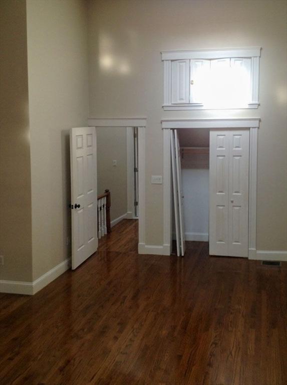 unfurnished bedroom with wood finished floors, baseboards, and a closet