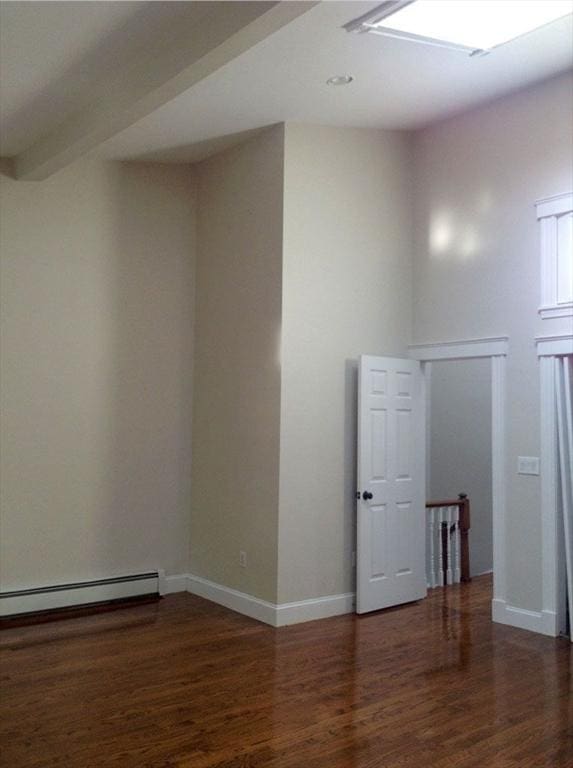 unfurnished room with wood finished floors, a baseboard radiator, and baseboards