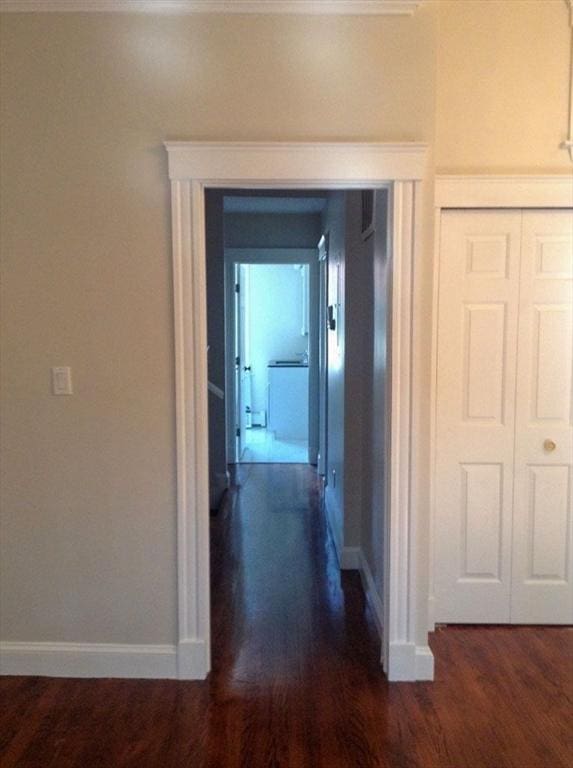 hallway with dark wood-style floors, baseboards, and washer / clothes dryer