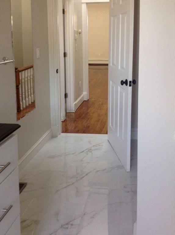 corridor featuring baseboards and marble finish flooring