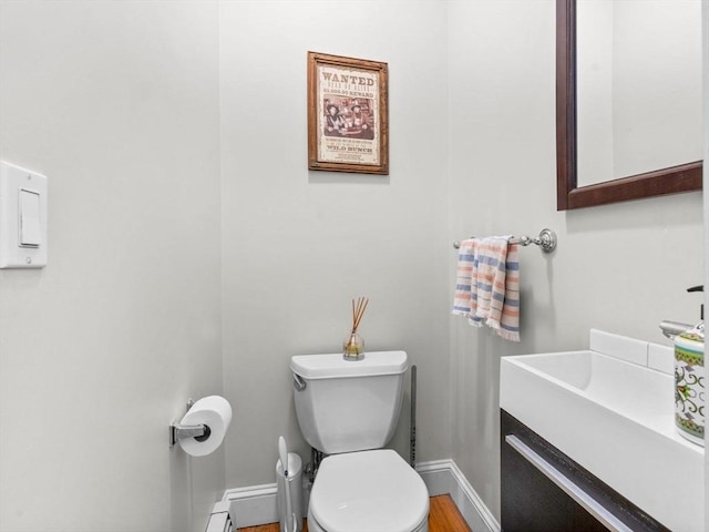 bathroom with baseboards, toilet, and vanity