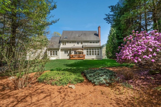 back of house with a lawn, a wooden deck, and a chimney