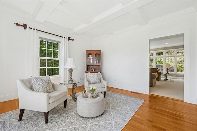 sitting room featuring baseboards, plenty of natural light, coffered ceiling, and wood finished floors