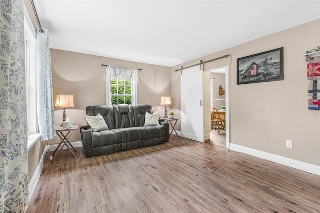 living room with a barn door, light wood-style floors, and baseboards