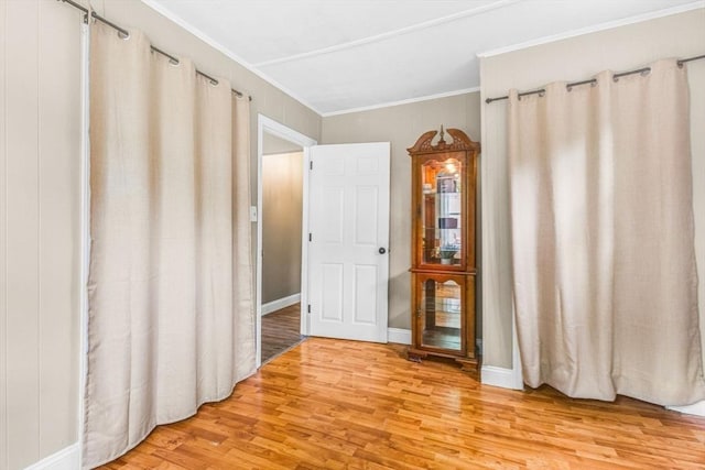 unfurnished bedroom featuring light wood-type flooring, crown molding, and baseboards