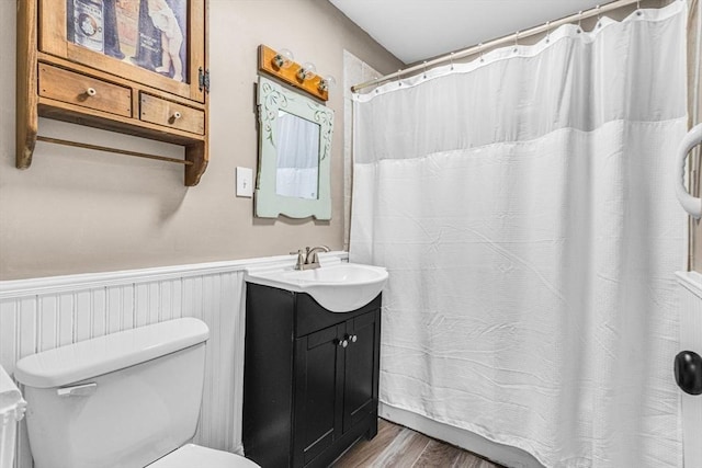 bathroom featuring toilet, a wainscoted wall, wood finished floors, vanity, and a shower with shower curtain