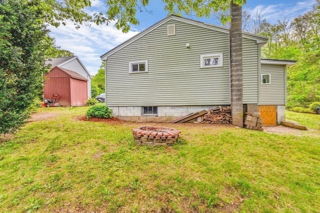 view of home's exterior with an outdoor fire pit and a lawn