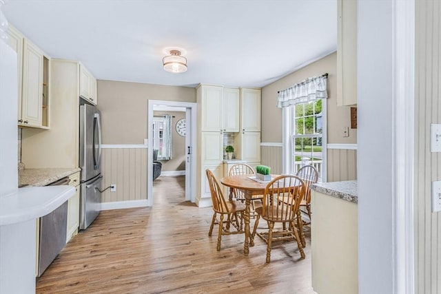 dining area featuring light wood-style flooring and baseboards