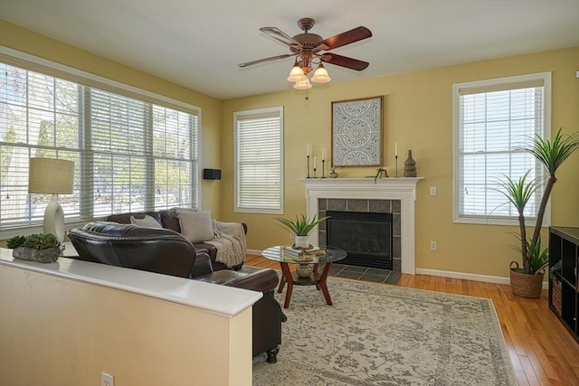 living room with a tile fireplace, ceiling fan, and hardwood / wood-style floors