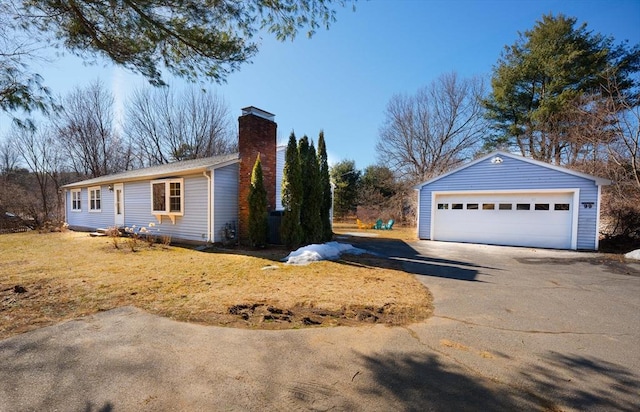 view of side of property with an outbuilding, a chimney, and a garage