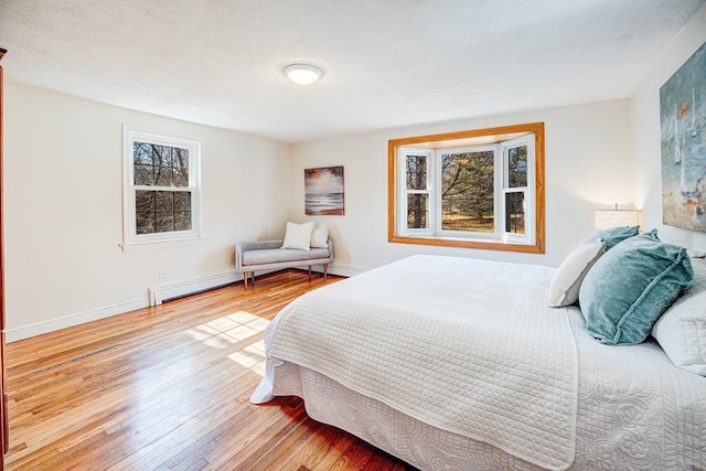 bedroom with baseboards, baseboard heating, hardwood / wood-style floors, and a textured ceiling