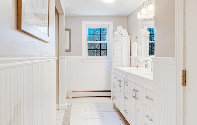 full bathroom with tile patterned floors, a baseboard radiator, vanity, and wainscoting