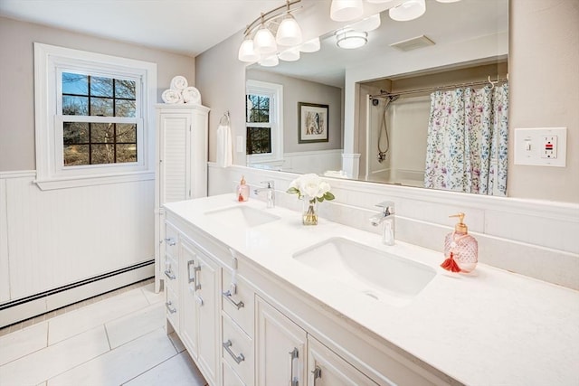 full bathroom featuring a baseboard heating unit, wainscoting, tile patterned flooring, and a sink