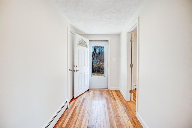 doorway featuring light wood-type flooring, baseboards, a textured ceiling, and a baseboard heating unit