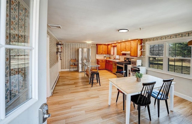 dining room featuring light wood finished floors, visible vents, wallpapered walls, and baseboards